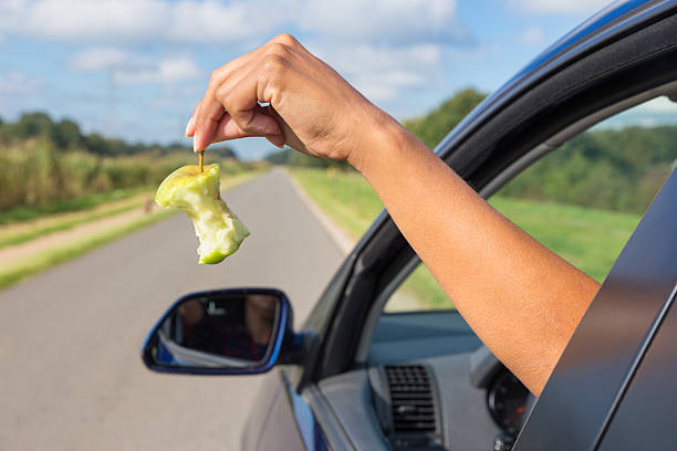 istock Female arm dropping apple core out car window 614983268
