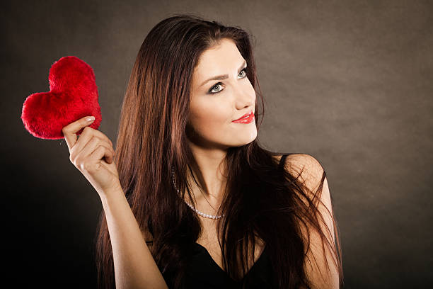 istock Beautiful woman holds red heart on black 614983668