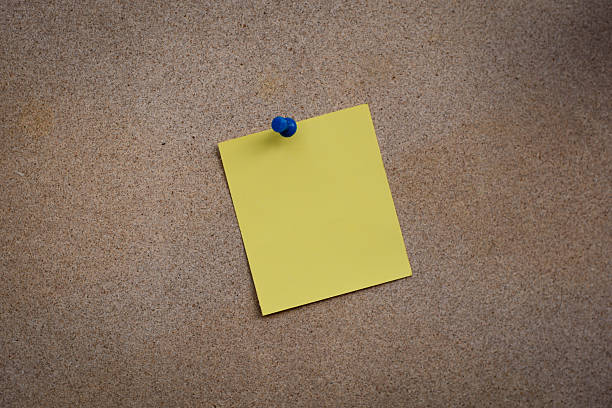 istock Blank yellow paper note pinned on cork board 614985624