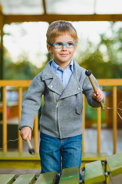 Close up portrait of cute boy playing xylophone outdoor stock photo