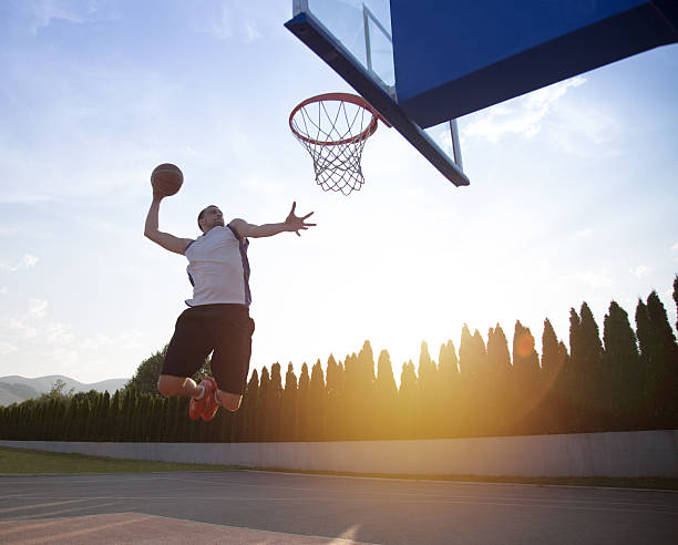 istock Young man jumping and making a fantastic slam dunk 614986784