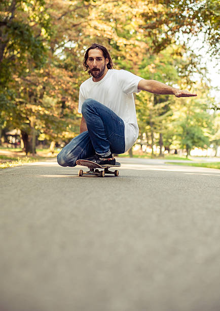 istock Skateboarder squatting on a skateboard and ride through the forest 614986794