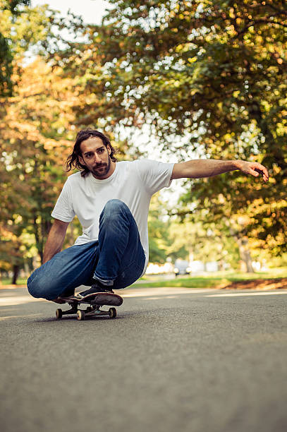 istock Skateboarder squatting on a skateboard and ride through the forest 614987062