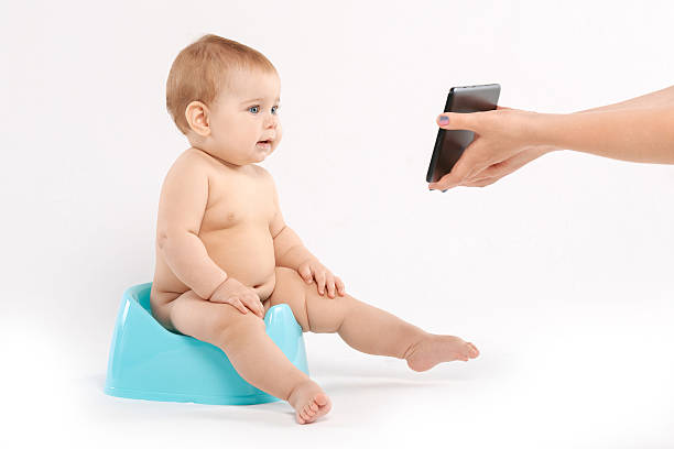 baby looks at a tablet baby sitting on a pot on a white background accustom stock pictures, royalty-free photos & images