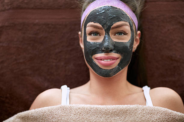 Pretty woman with cosmetic black mask on face Pretty woman with cosmetic black mask on face, concept - beauty, healthcare. women facial mask mud cucumber stock pictures, royalty-free photos & images