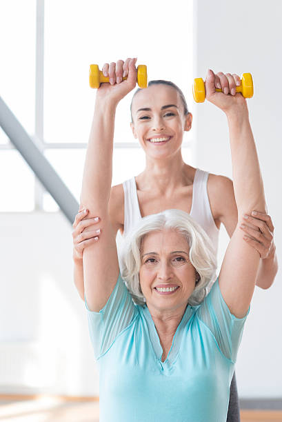 istock Cheerful pleasant woman holding small rubber dumbbells up 614993206