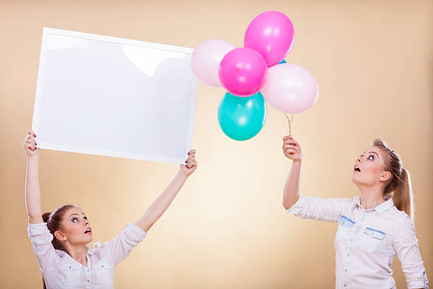istock Two girls with blank board and balloons 614993826