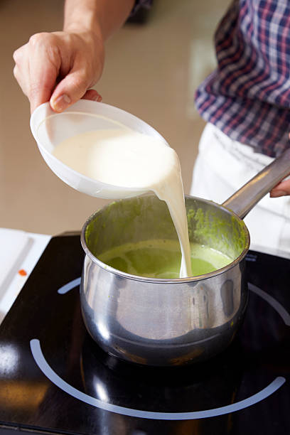 istock Hand adding milk cream into pot of pea soup 614995070