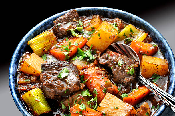 Food Dishes Beef stew  with carrots and potatoes n blue bowl with spoon. beef stew stock pictures, royalty-free photos & images