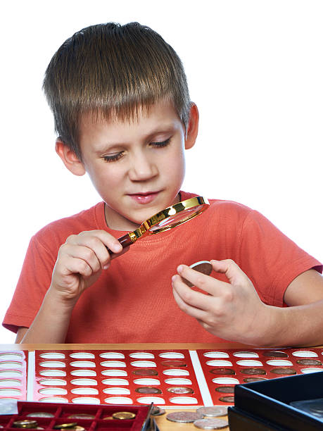 istock Boy examines coin through magnifying glass isolated 614996778