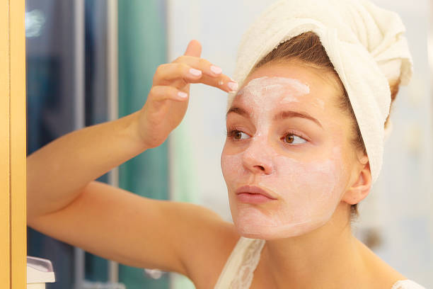 istock Woman applying mask cream on face in bathroom 614997700