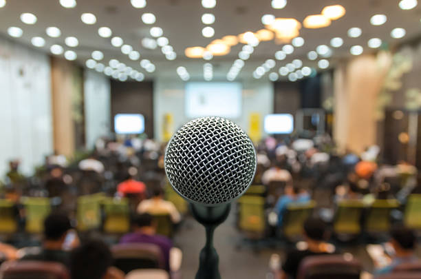 Microphone over the Abstract blurred photo of conference hall or