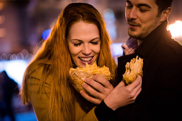 istock Couple having fun - eating together in street 615073268
