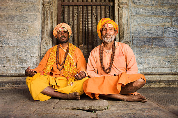 Sadhu - indian holymen sitting in the temple Sadhu - indian holymen sitting in the temple. In Hinduism, sadhu, or shadhu is a common term for a mystic, an ascetic, practitioner of yoga (yogi) and/or wandering monks. The sadhu is solely dedicated to achieving the fourth and final Hindu goal of life, moksha (liberation), through meditation and contemplation of Brahman. Sadhus often wear ochre-colored clothing, symbolizing renunciation.http://bhphoto.pl/IS/nepal_380.jpg caste system stock pictures, royalty-free photos & images