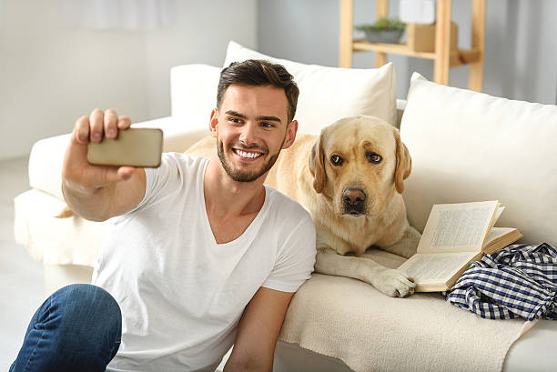 istock bearded man showing his dog a phone 615075394