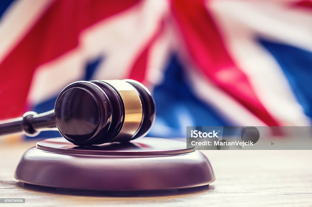 Judges wooden gavel with UK flag in the background. Judges wooden gavel with UK flag in the background. Symbol for jurisdiction. UK Stock Photo