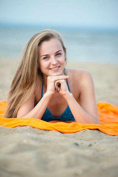istock Young lady sunbathing on a beach. Beautiful woman posing at 615077220