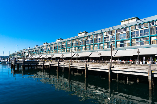 Finger wharf restaurants and hotel in Woolloomooloo bay with unrecognisable people in the distance. Sydney, Australia