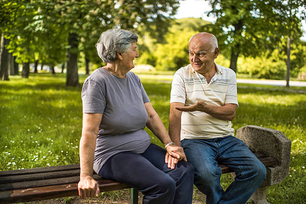 istock Smiling old couple communicating on a bench in the park. 615080304