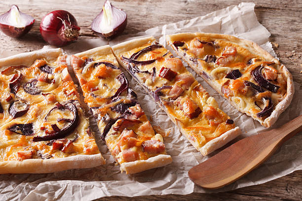istock flammkuchen with bacon and red onion on the paper. Horizontal 615081222