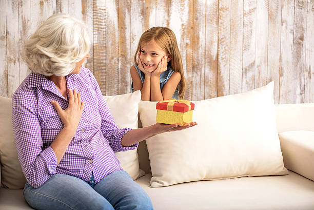 istock Pretty child congratulating granny with event 615081788