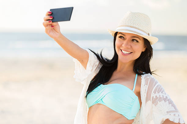 istock Playful woman poses for selfie on the beach 615086536