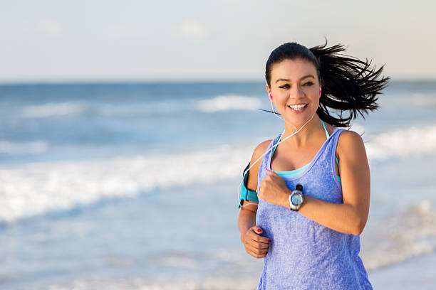 istock Smiling athletic woman jogs on the beach 615086756