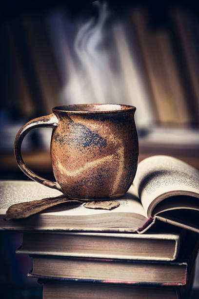 istock Cup with hot beverage and steam on stack of books 615087814