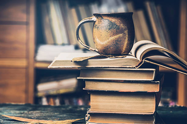 istock Mug with hot beverage and stack of books 615087898