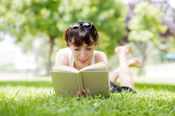 istock Young woman reading a book in a park 615088082