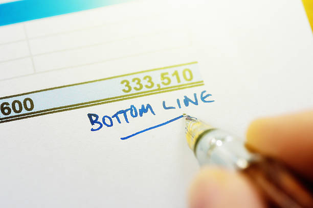 "bottom line" wird in tinte auf einem finanzdokument geschrieben - the end report finishing document stock-fotos und bilder