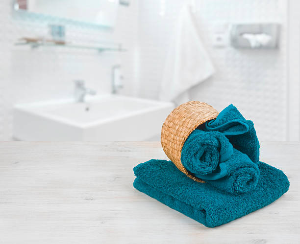 istock Green-blue folded towels in wicker basket over defocused bathroom 615093152