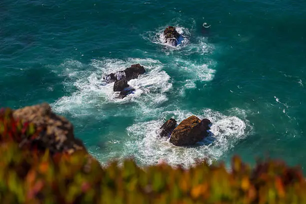 Watersplashes from waves crushing over rocks in the ocean from above