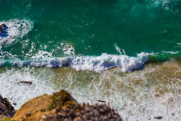 Watersplashes from waves crushing over rocks in the ocean from above