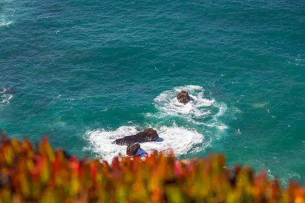 Watersplashes from waves crushing over rocks in the ocean from above