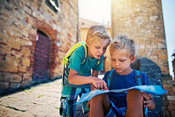 istock Little tourist boys checking map in a small Italian town 615098084