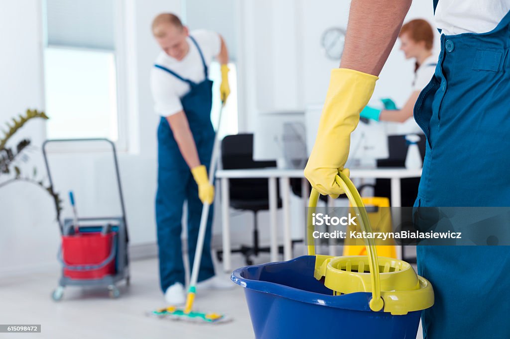 Person holding a mop pail Image of person holding mop pail and man cleaning floor Cleaning Stock Photo