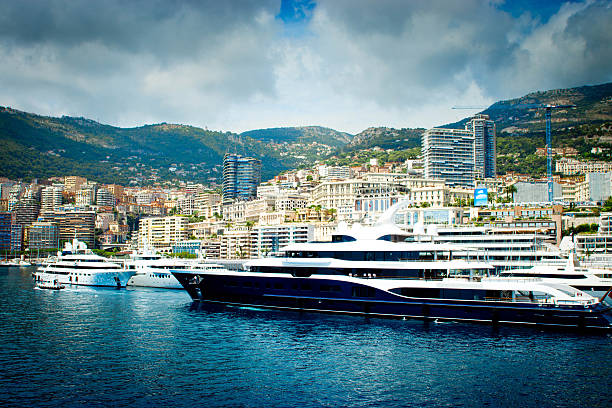 Monte Carlo, Monaco - July 30, 2015: A luxury motor yacht in Monaco marina moored. In the background are other luxury vessels with apartments and hotels on the hillside.