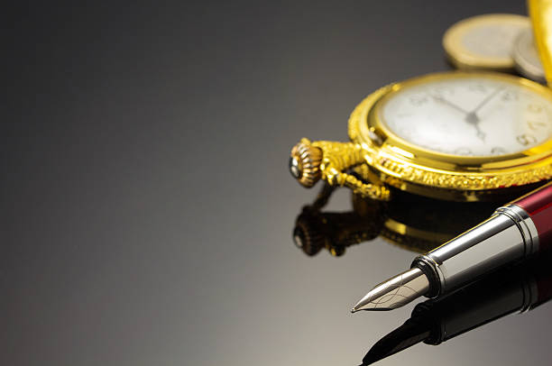 istock pocket watch and ink pen on black 615100830