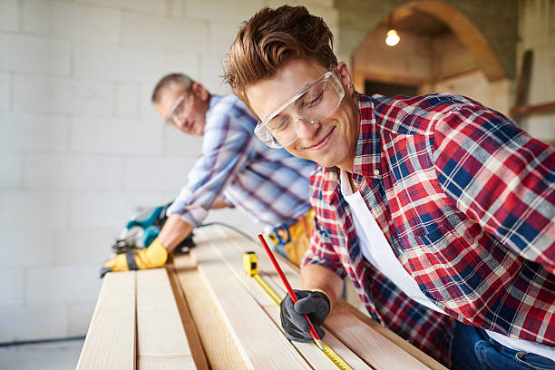 istock Younger carpenter draws measurements by pencil 615104248