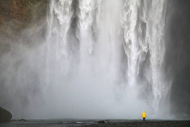 enorme cascada y persona en chaqueta amarilla - large waterfall fotografías e imágenes de stock