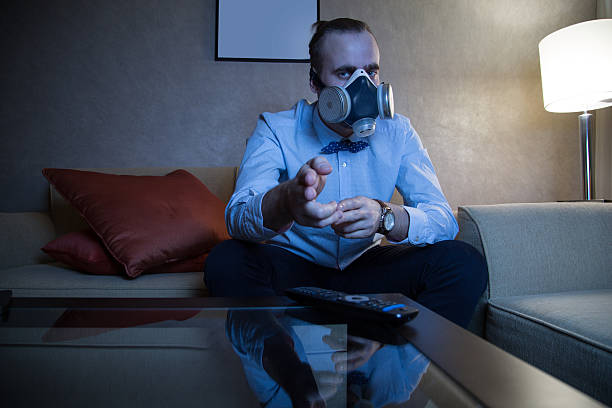 Man in respirator watching TV stock photo