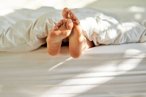 Shot of a man's feet poking out from the bottom of his bed