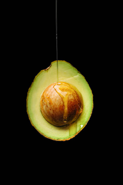 ripe avocado cut in half on black background ripe avocado cut in half on black background olive oil pouring antioxidant liquid stock pictures, royalty-free photos & images