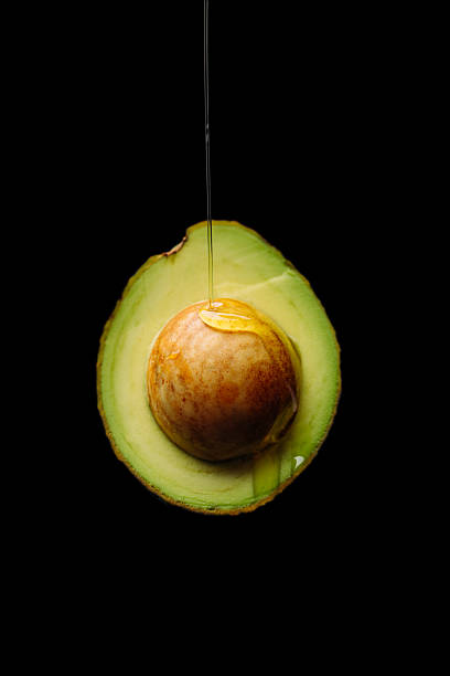 ripe avocado cut in half on black background ripe avocado cut in half on black background olive oil pouring antioxidant liquid stock pictures, royalty-free photos & images