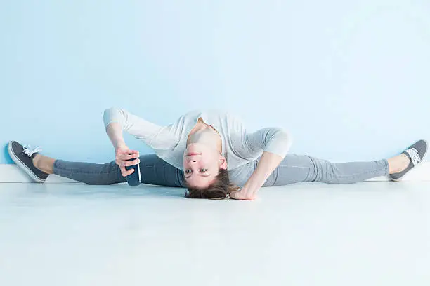 A female gymnast, fit and flexible, taking a selfie whilst being a contortionist.