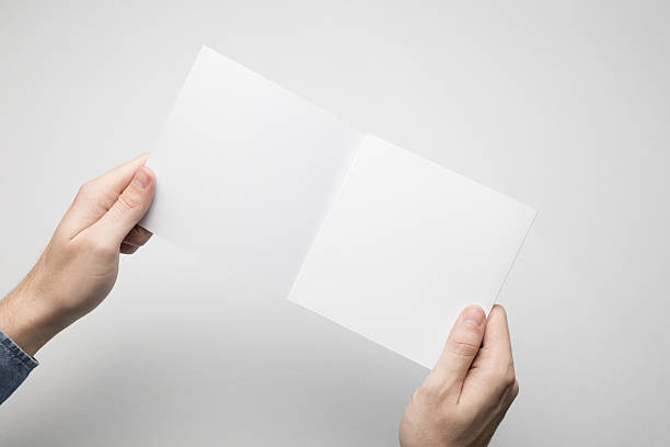 istock Hands are holding a Square Bi-Fold white paper poster. 615116340