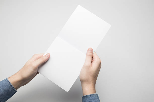 istock Hands are holding a Square Bi-Fold white paper poster. 615116398