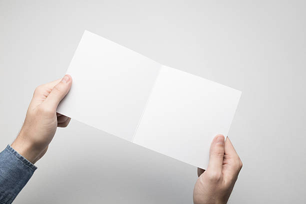 istock Hands are holding a Square Bi-Fold white paper poster. 615116702