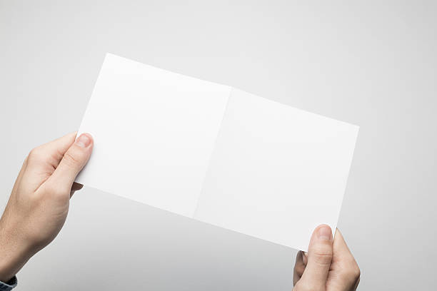 istock Hands are holding a Square Bi-Fold white paper poster. 615116778